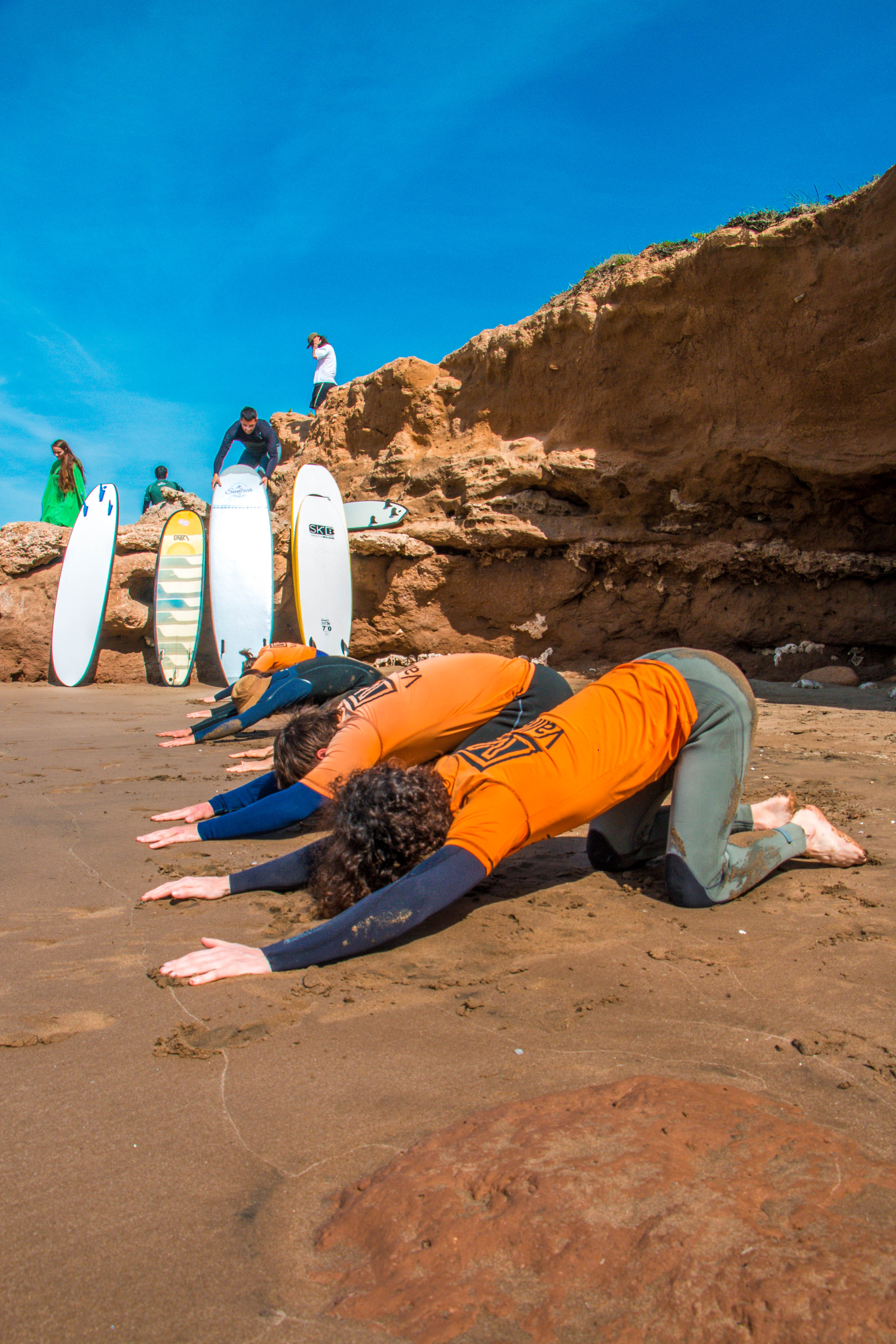 Grupo haciendo estiramiento en la playa antes de surfear